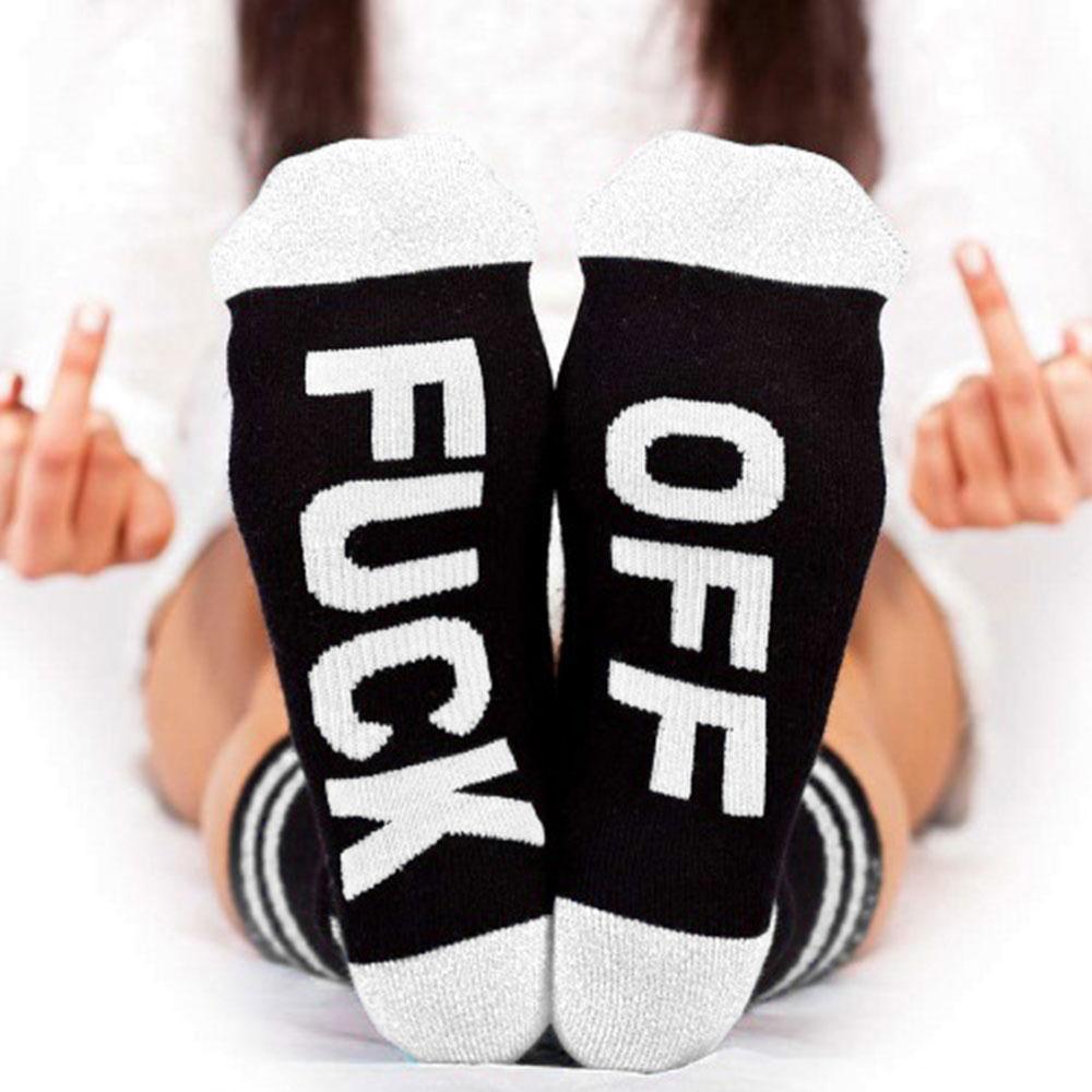 A novelty pair of black and white socks with bold writing on the sole saying "FUCK OFF"